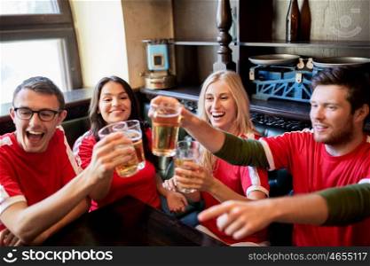 sport, soccer, people and leisure concept - happy friends or football fans clinking beer glasses at bar or pub