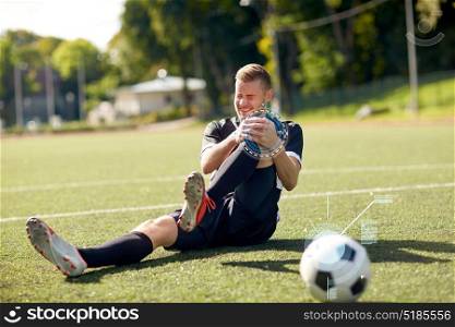 sport, sports injury and people - injured soccer player with ball on football field. injured soccer player with ball on football field