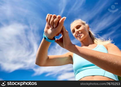 sport, technology and healthy lifestyle concept - close up of happy smiling young woman with fitness tracker outdoors. smiling young woman with fitness tracker outdoors