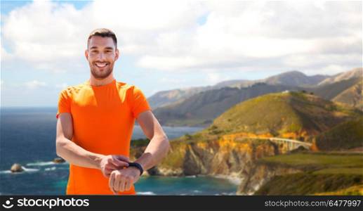 sport, technology and healthy lifestyle concept - man with fitness tracker training over big sur hills and pacific ocean background in california. man with fitness tracker training outdoors. man with fitness tracker training outdoors