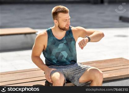 sport, technology and healthy lifestyle concept - young man with fitness tracker in city. man with fitness tracker in city