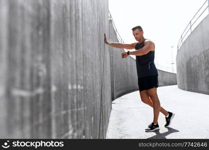 sport, technology and healthy lifestyle concept - young man with fitness tracker on city street. young man with fitness tracker on city street