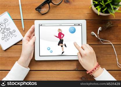 sport, technology and people concept - close up of woman with fitness application on tablet pc computer screen on wooden table
