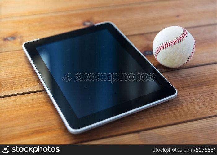sport, technology, game and objects concept - close up of baseball ball and tablet pc computer on wooden floor
