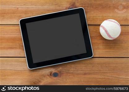 sport, technology, game and objects concept - close up of baseball ball and tablet pc computer on wooden floor
