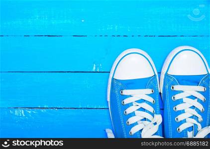 sport textile blue sneakers with white laces on a blue wood background of parallel boards, empty space at the top