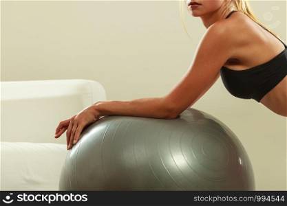 Sport, training, gym and lifestyle concept. Young attractive slim woman in sportswear doing fitness exercises with fit ball at home