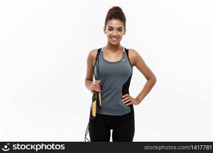 Sport, training, lifestyle and Fitness concept - portrait of beautiful happy African American woman exercising with jumping rope. Isolated on white studio background. Sport, training, lifestyle and Fitness concept - portrait of beautiful happy African American woman exercising with jumping rope. Isolated on white studio background.