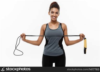 Sport, training, lifestyle and Fitness concept - portrait of beautiful happy African American woman exercising with jumping rope. Isolated on white studio background. Sport, training, lifestyle and Fitness concept - portrait of beautiful happy African American woman exercising with jumping rope. Isolated on white studio background.