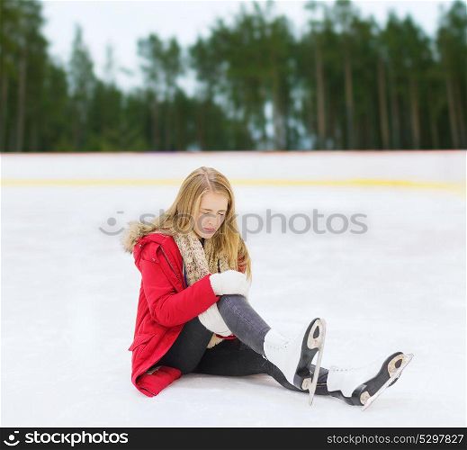 sport, trauma and winter concept - young woman with knee injury suffering from pain on skating rink. young woman with knee injury on skating rink
