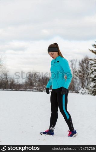Sport winter people concept. Young lady doing workout in park. Beautiful girl jogging around outside, enjoying wintry time. Woman wearing blue top and leggins.. Young lady doing workout in park.
