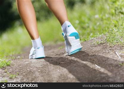 Sport woman. Close up of female feet running on road