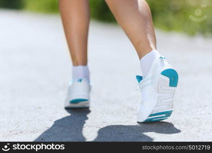 Sport woman. Close up of female feet running on road