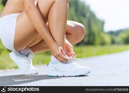 Sport woman. Close up of woman in sport wear tying shoelace