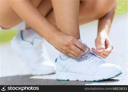 Sport woman. Close up of woman in sport wear tying shoelace