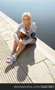 Sport woman relax on pier sitting by water summer day