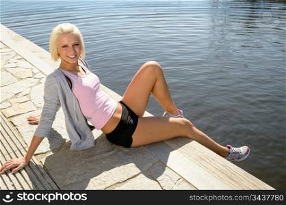 Sport woman summer relax sitting by water pier
