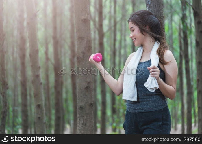 Sport young woman girl lifestyle relax holding fitness dumbbell workout in forest nature park with copy space