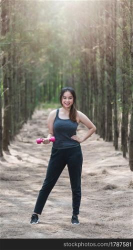 Sport young woman girl lifestyle relax holding fitness dumbbell workout in forest nature park with copy space
