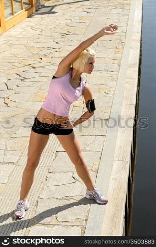 Sport young woman stretch body by water pier summer day