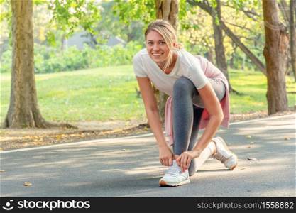 Sportgirl ties her sneakers in the park. Athletic woman tying shoelaces while getting ready to run.