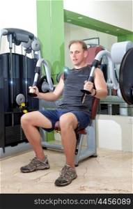 sporting man is engaged in training in fitness center in a gym on trainers