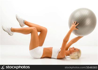 Sportive blond woman exercising with fitness ball on white background
