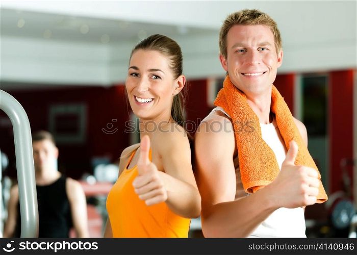 Sportive couple in gym or fitness club looking at the viewer