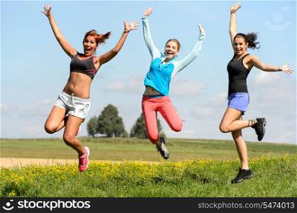 Sportive friends jumping cheerful on sunny meadow teenage girls