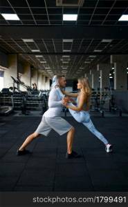 Sportive love couple doing stretching exercise, fitness training in gym. Athletic man and woman on workout in sport club, active healthy lifestyle, physical wellness. Couple doing stretching exercise, fitness training
