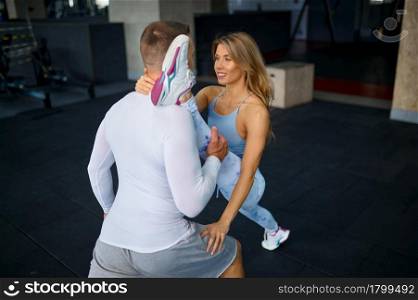 Sportive love couple doing stretching exercise, fitness training in gym. Athletic man and woman on workout in sport club, active healthy lifestyle, physical wellness. Couple doing stretching exercise, fitness training