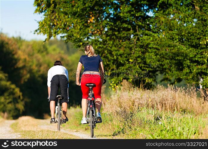 Sportive Man and woman exercising with bicycles outdoors, they are a couple