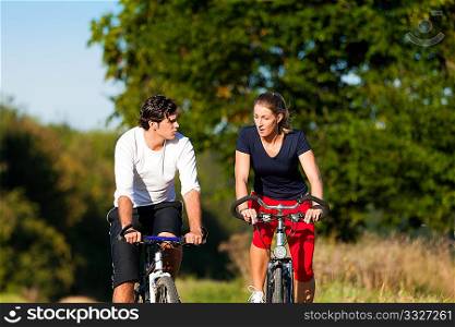 Sportive Man and woman exercising with bicycles outdoors, they are a couple