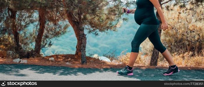 Sportive Pregnant Woman Jogging in the Mountainous Forest in Sunny Day. Enjoying the Walk Among Fresh Pine Trees. Body Part. Healthy Pregnancy.. Pregnant Woman Jogging in the Park