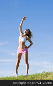 Sportive stretching young happy woman meadows blue summer sky