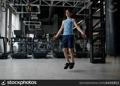 Sportive teenage boy skipping rope while training at gym. Children workout indoors and wellness concept. Sportive teenage boy skipping rope while training at gym