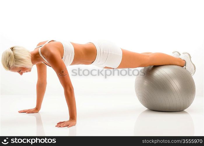 Sportive woman doing pushup exercise on fitness ball white background