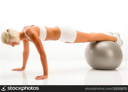 Sportive woman doing pushup exercise on fitness ball white background