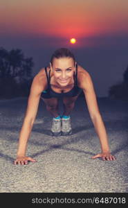 Sportive woman doing pushups outdoors, attractive female doing fitness exercises on beautiful sunset, healthy lifestyle of a young people. Sportive woman doing pushups outdoors