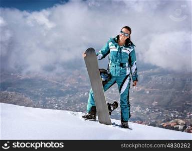 Sportive woman standing on the top of mountain with snowboard in hands, active wintertime holidays, extreme lifestyle concept&#xA;