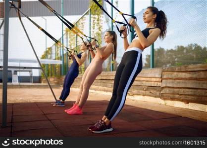 Sportive women doing fit exercise with ropes on sports ground, outdoors group training. Female athletes in sportswear, team fitness workout, teamwork. Sportive women, outdoors group training