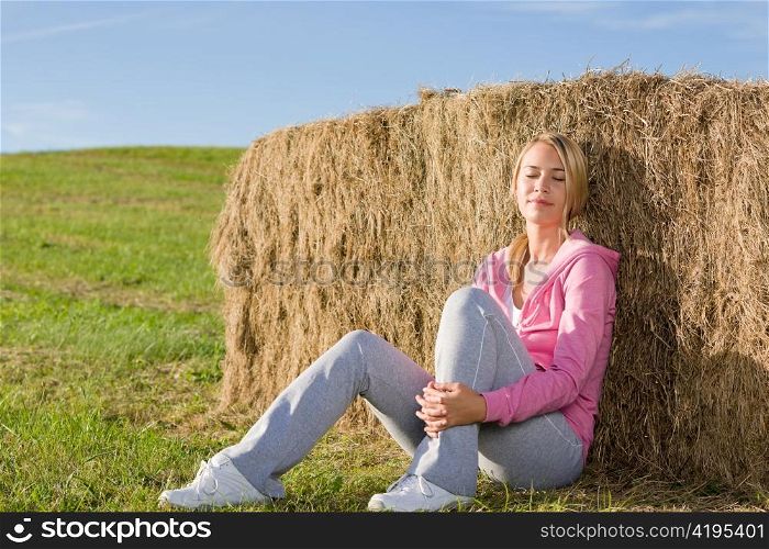 Sportive young woman relax lean against hay bales sunset countryside