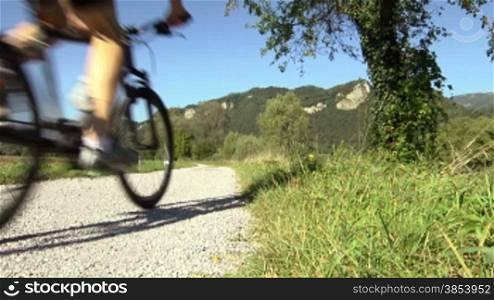 Sports activity: young adult cyclist riding mountain bike in the countryside on dirt road. Crane shot