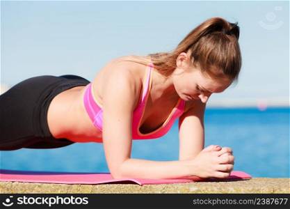 Sports and activities concept. Slim fit attractive woman exercising stretching outdoor. Young motivated girl training in sporty clothes.. Young woman exercising outside
