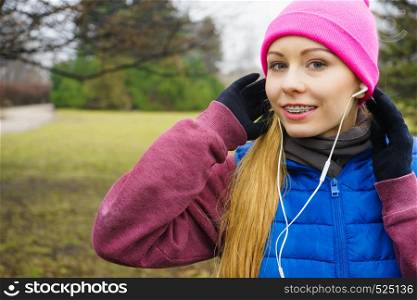 Sports and activities in cold time. Slim fit fitness woman outdoor. Athlete teen girl wearing warm sporty clothes outside listening to music. Teenage sporty girl listening to music outdoor.