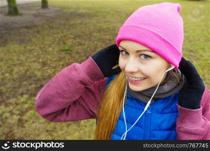 Sports and activities in cold time. Slim fit fitness woman outdoor. Athlete teen girl wearing warm sporty clothes outside listening to music. Teenage sporty girl listening to music outdoor.