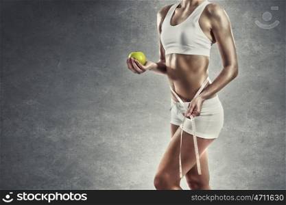 Sports and healthy nutrition. Woman measuring her waist while holding apple in hand