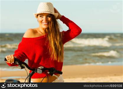 Sports and recreation. Attractive smiling woman with bicycle walks on beach near to sea. Young long haired gorgeous tourist spends time on seaside.. Beauty tourist with bike on beach.