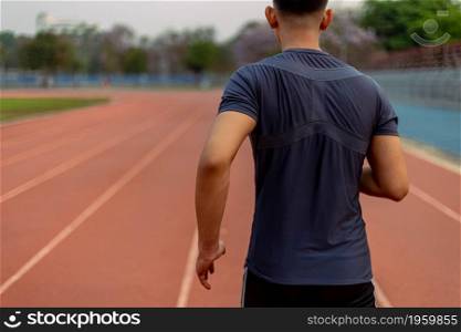 Sports and recreation concept a young male adult running in low speed in the sports stadium as his healthy routine in the evening.