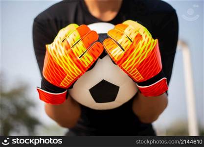 Sports and recreation concept a young male goalkeeper using his both hands catching the ball as preventing the opposing team from scoring.